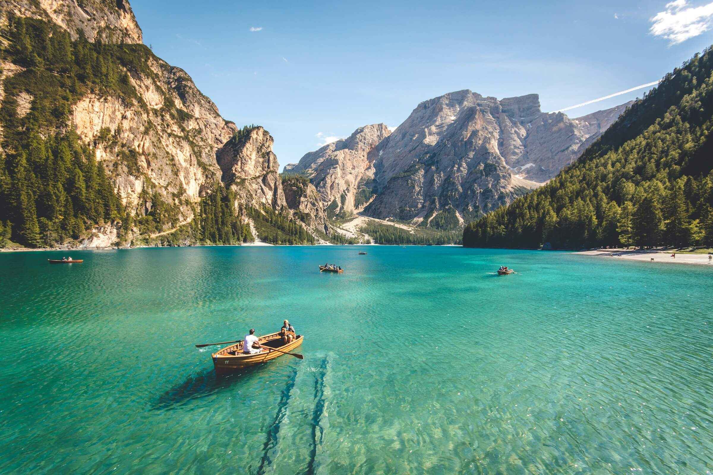 Turquoise mountain lake with wooden boats and rocky peaks